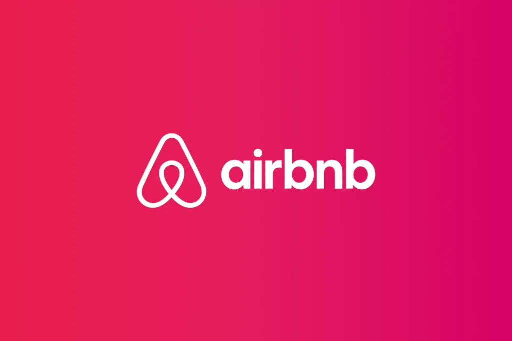 Prenota Logo ufficiale Airbnb con simbolo Bélo bianco su sfondo sfumato rosa e rosso, brand di piattaforma per affitti brevi e case vacanza online.
